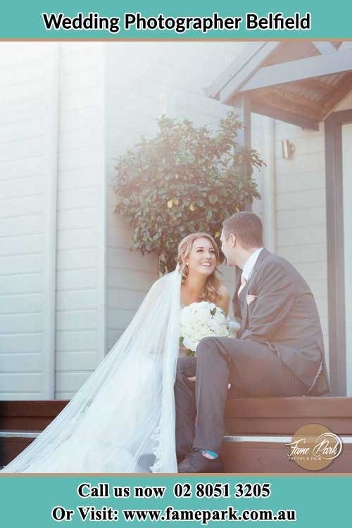 Photo of the Bride and the Groom looking each other while sitting at the staircase Belfield NSW 2191