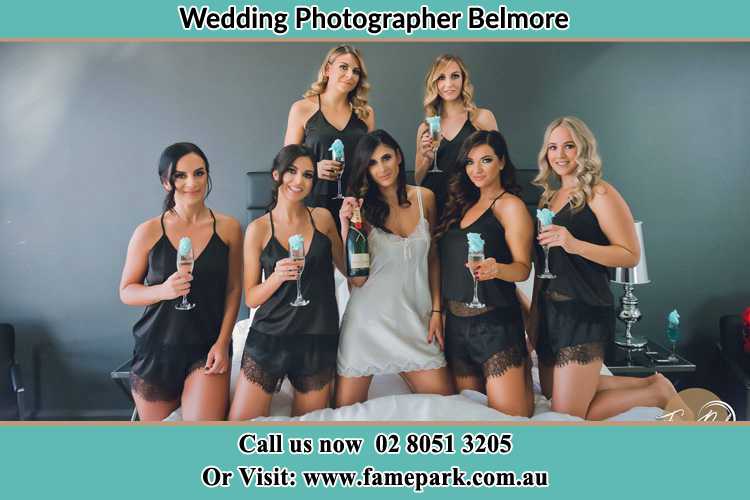 Photo of the Bride and the bridesmaids wearing lingerie and holding glass of wine on bed Belmore NSW 2192