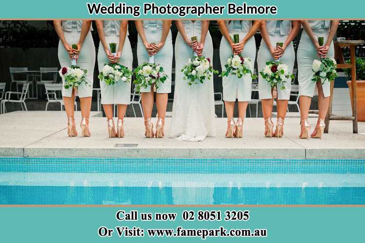 Behind photo of the Bride and the bridesmaids holding flowers near the pool Belmore NSW 2192