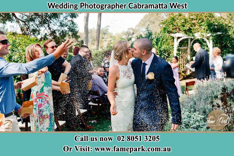 Photo of the Bride and the Groom kissing while showering rice by the visitors Cabramatta West NSW 2166