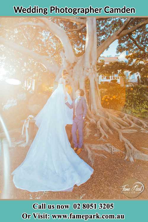 Photo of the Bride and the Groom looking each other besides the tree Camden NSW 2570