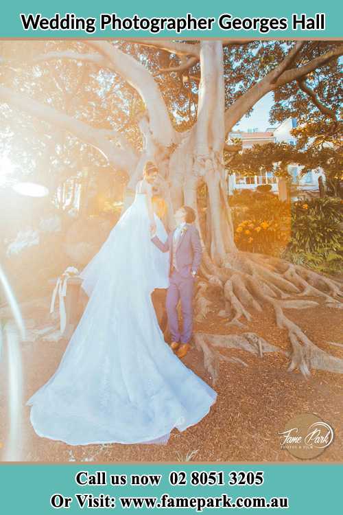 Photo of the Bride and the Groom looking each other besides the tree Georges Hall NSW 2198