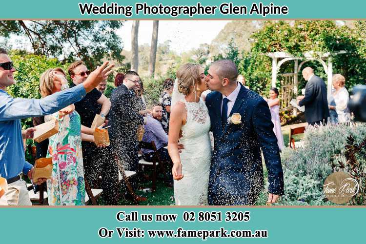 Photo of the Bride and the Groom kissing while showering rice by the visitors Glen Alpine NSW 2560