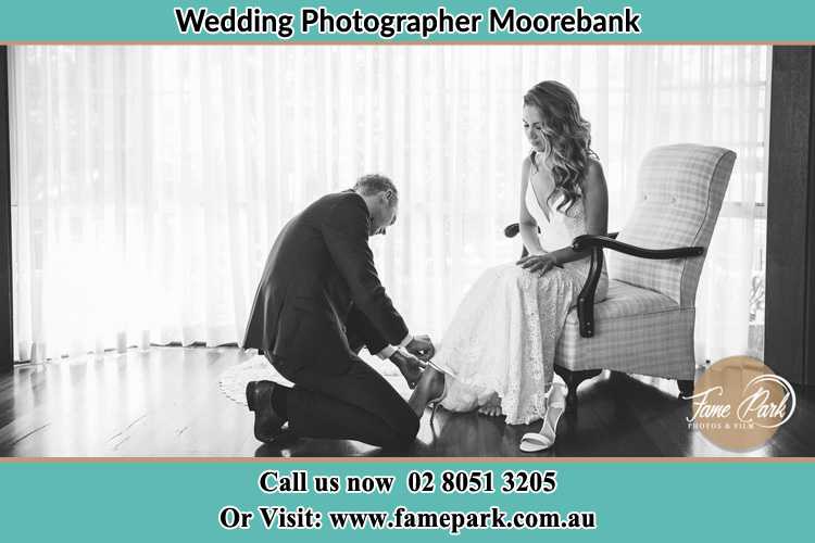 The Bride is being helped by the Groom trying to put on her shoes Moorebank NSW 2170