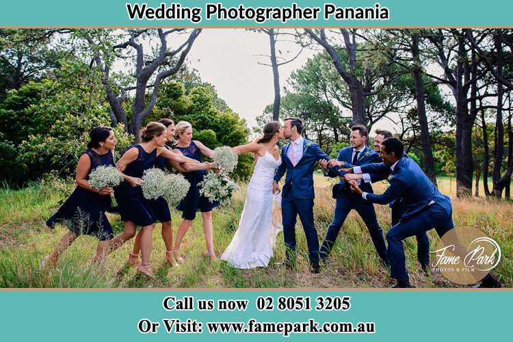 Photo of the Bride and the Groom kissing while teasing by the entourage Panania NSW 2213