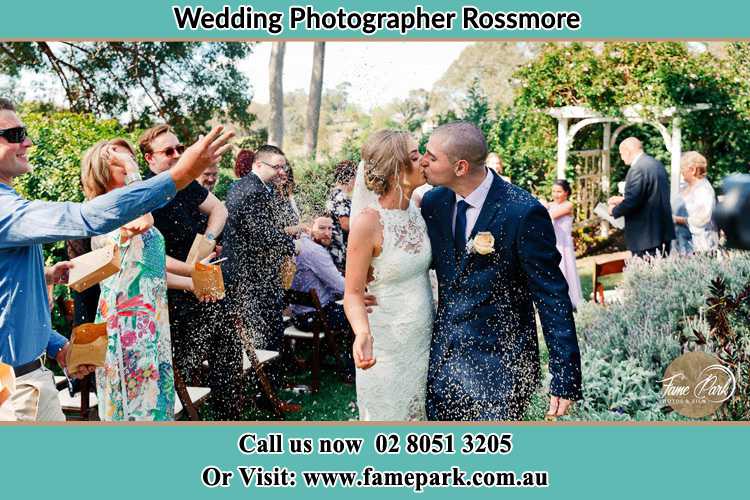 Photo of the Bride and the Groom kissing while showering rice by the visitors Rossmore NSW 2557